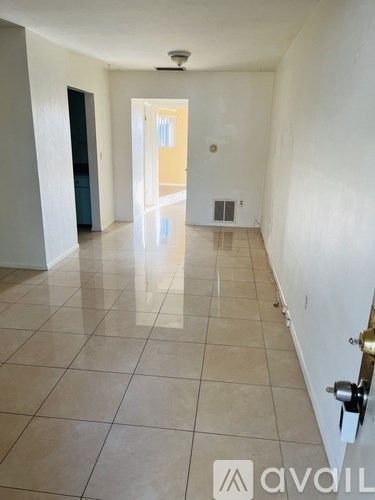 A hallway with tiled floors and white walls.