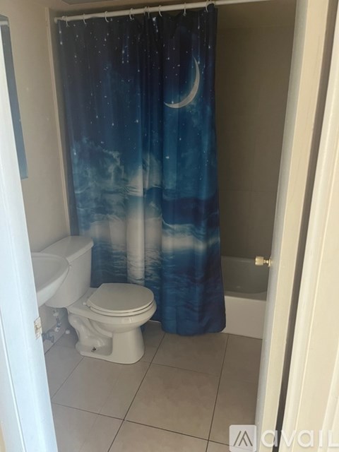 A bathroom with a toilet and a shower curtain with a night sky print.