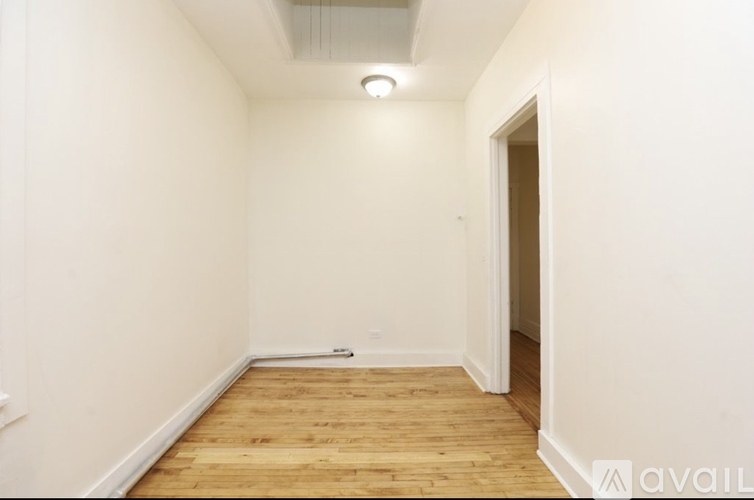 A room with wooden flooring and white walls.