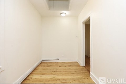 A room with wooden flooring and white walls.