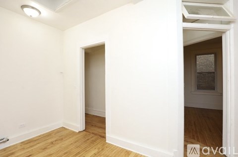 A room with a white wall and wooden floor.
