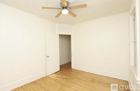 A room with a ceiling fan and wooden flooring.
