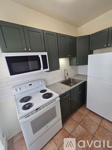 A kitchen with white appliances and green cabinets.