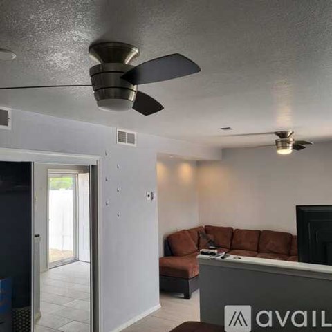 A living room with a brown couch and a ceiling fan.