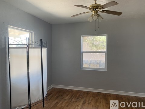 A room with a ceiling fan and a window with a view of trees.