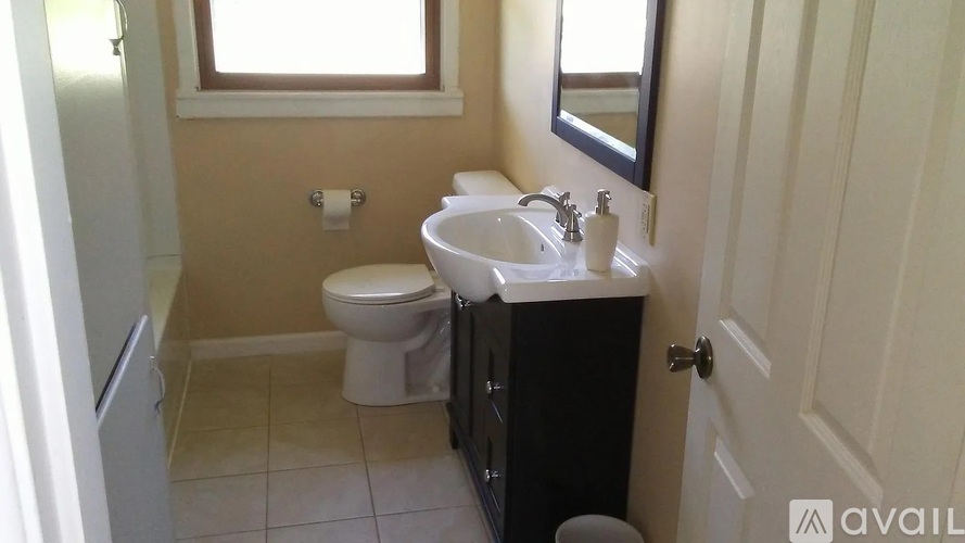 A bathroom with a toilet, sink, and mirror.