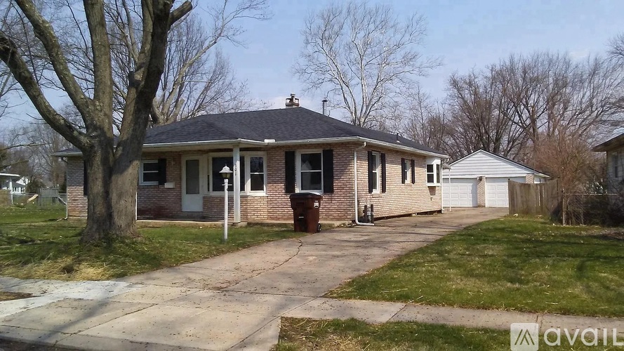 A house with a front yard and a tree in front of it.
