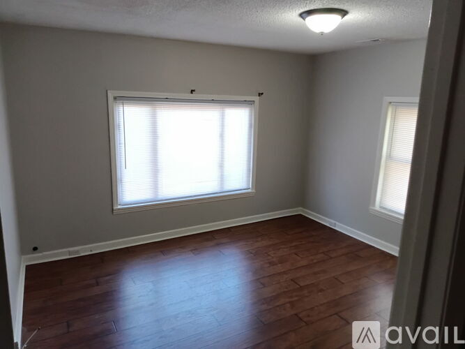 A room with wooden floors and a window with blinds.