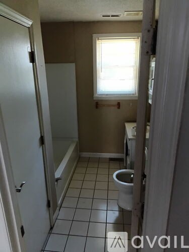 A bathroom with a toilet, tub, and window.