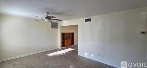 A spacious room with a ceiling fan and a door at the end.