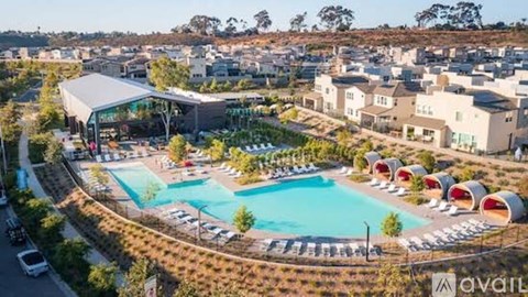 A large swimming pool surrounded by a grassy area and a building with a white canopy.