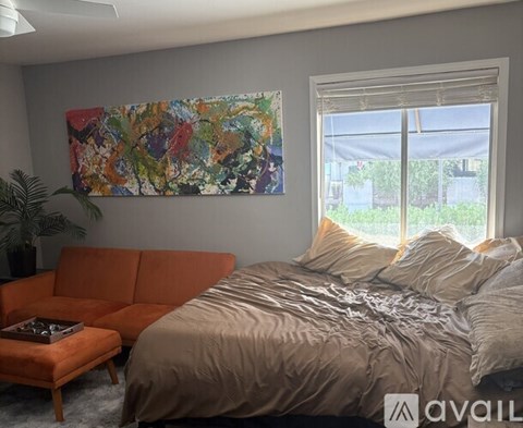 A bedroom with a bed, a couch, and a painting on the wall.