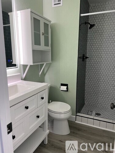 A white toilet sits in a bathroom next to a shower.