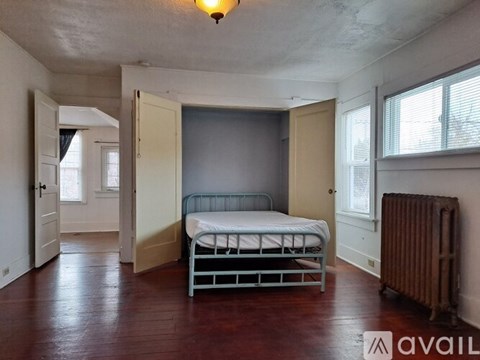 A bedroom with a bed, a radiator, and a window.