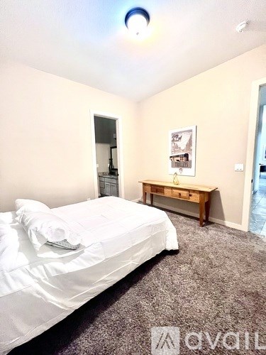 A bedroom with a white bed and a wooden bench.