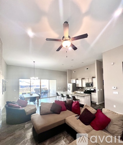 A living room with a brown couch and a ceiling fan.
