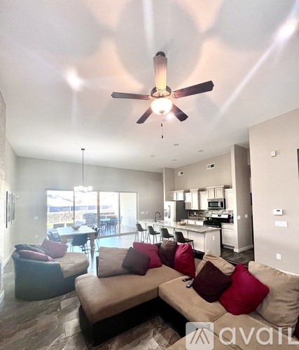 A living room with a brown couch and a ceiling fan.
