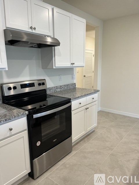 A kitchen with a stove top oven and white cabinets.