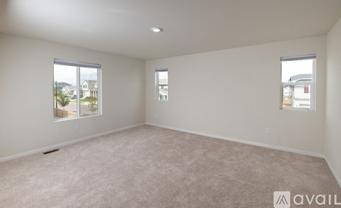 A spacious room with carpeted floor and two windows.