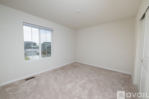 A room with a carpeted floor and a window showing a view of other buildings.