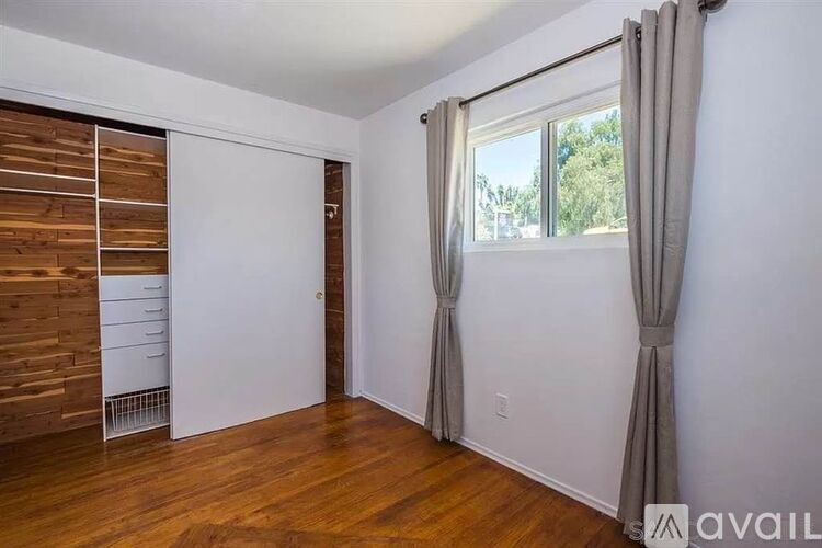 A room with a window, curtains, and a wooden panel on the wall.