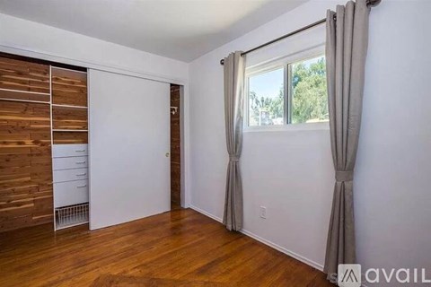 A room with a window, curtains, and a wooden panel on the wall.