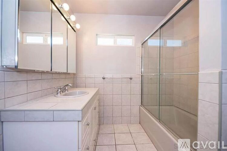 A bathroom with a sink, mirror, and shower.