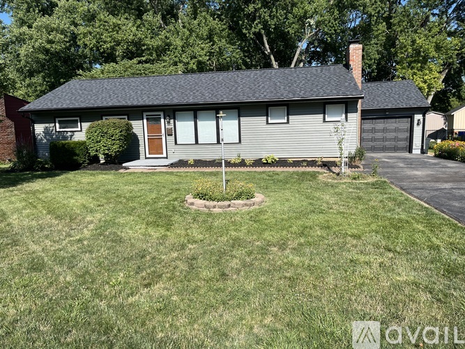 A house with a brown door and a grey roof is surrounded by green grass.