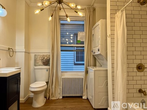 A bathroom with a toilet, sink, and a window with a view of a building outside.