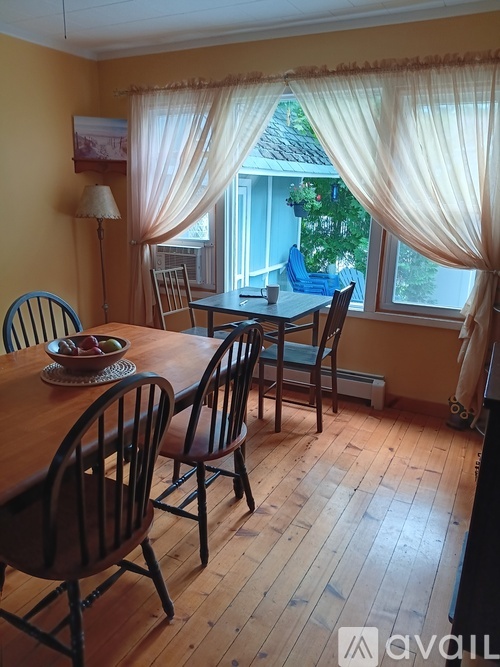 A dining room with a table set for two and a view of the backyard.
