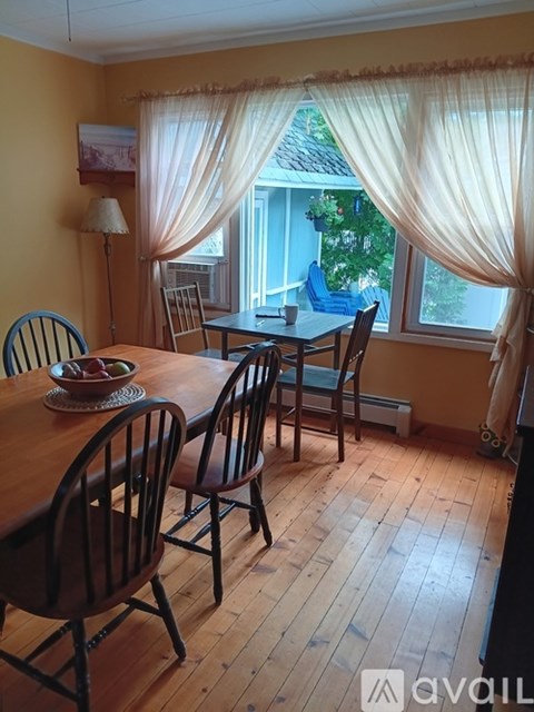 A dining room with a table set for two and a view of the backyard.