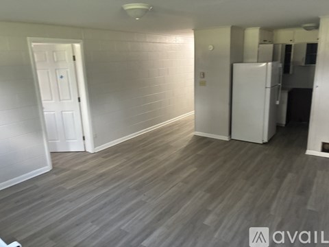 A room with a white door and a white fridge.