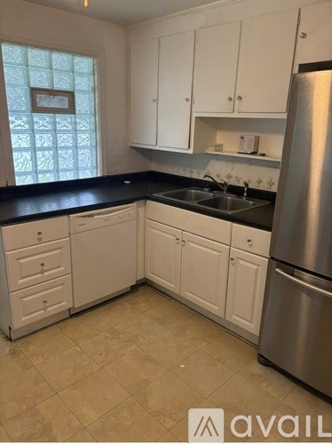 A kitchen with white cabinets and a stainless steel refrigerator.