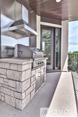 A modern outdoor kitchen with a stone counter and stainless steel appliances.