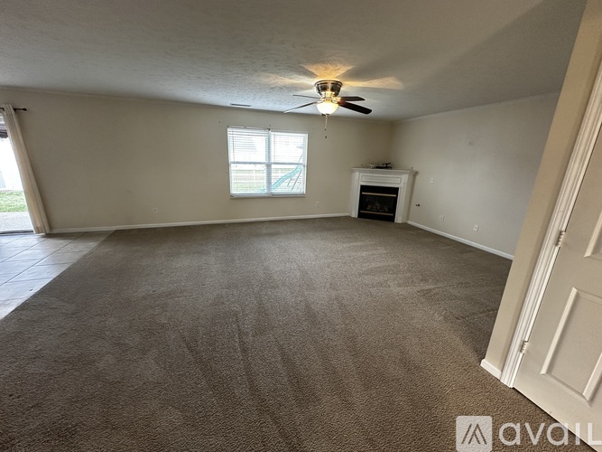 A room with a carpeted floor, a ceiling fan, and a window with blinds.