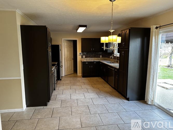 A kitchen with black cabinets and a tile floor.