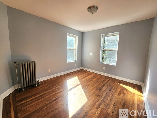 A room with wooden floors and two windows.