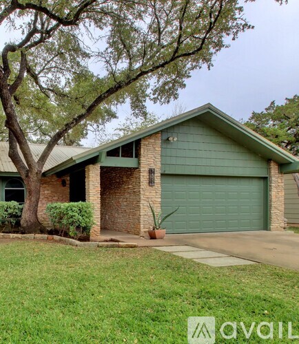 A house with a green garage door and a tree in front.