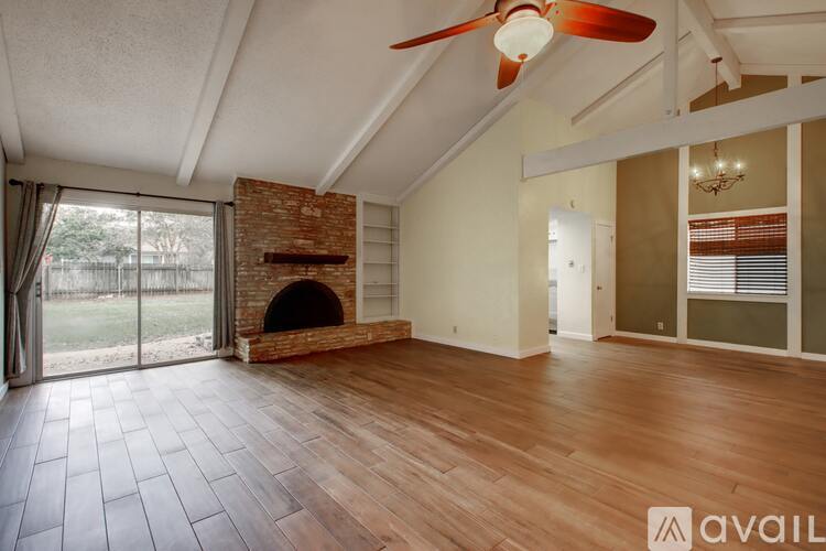 A spacious room with a brick fireplace and wooden flooring.
