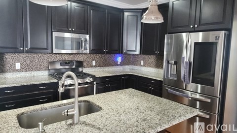 A kitchen with black cabinets and stainless steel appliances.