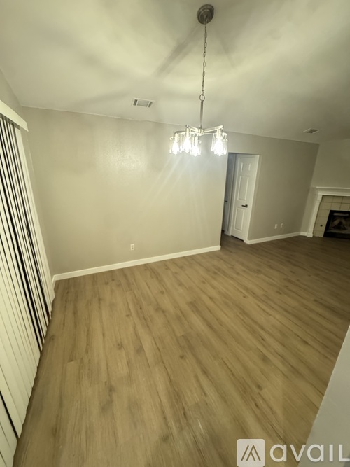 A room with wooden flooring and a chandelier hanging from the ceiling.