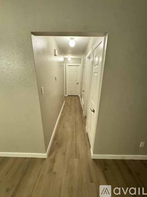 A hallway with wood flooring and white walls.