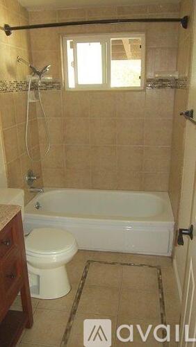 A bathroom with a toilet, tub, and window.