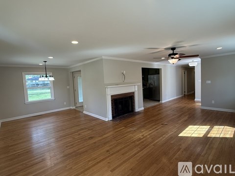 A spacious room with wood flooring and a fireplace.