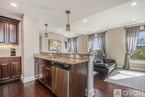 A kitchen with a black dishwasher and a black sofa.