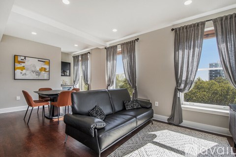 A living room with a black leather couch and a painting on the wall.