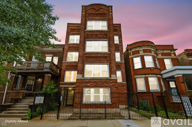 A red brick building with a black fence in front.