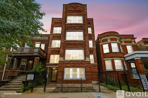 A red brick building with a black fence in front.