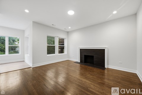 A spacious room with a fireplace and wooden flooring.