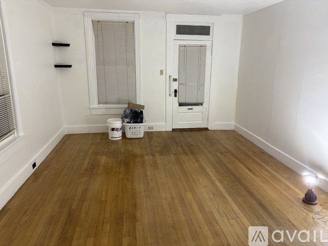 A room with wooden flooring and two doors, one of which is open.